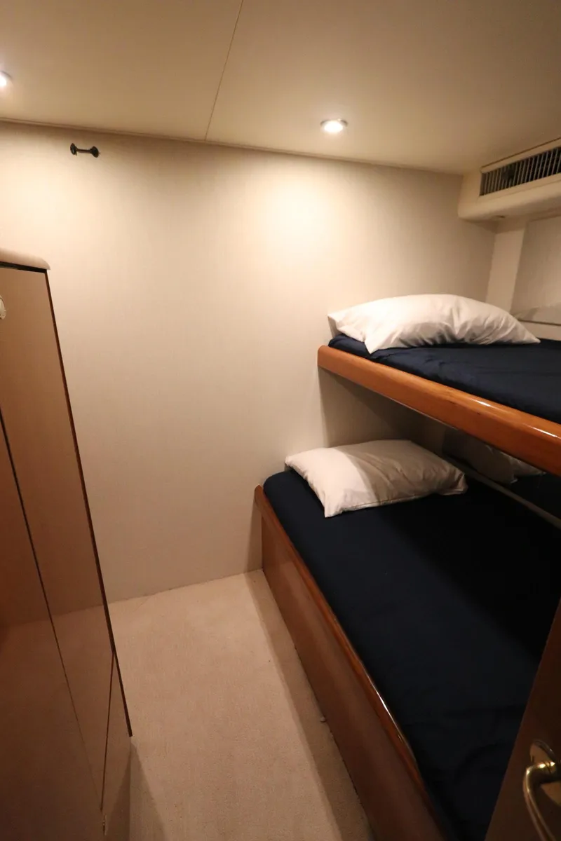 Slide: The Image of Bunk beds in a 2000 Viking 65 yacht cabin, featuring cozy bedding and warm lighting. - 14