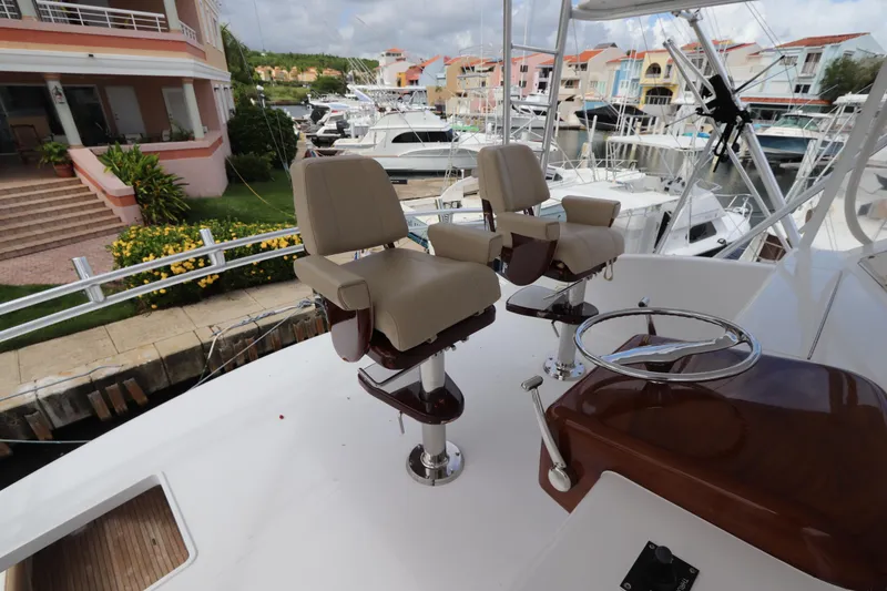 Slide: The Image of 2000 Viking 65 yacht helm with dual captain chairs in marina setting. - 18