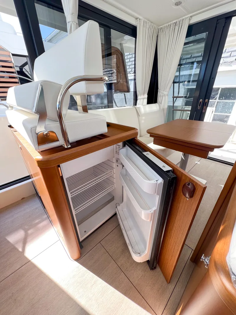 Slide: The Image of 2023 Beneteau Swift Trawler 35 interior with open fridge and seating area. - 10