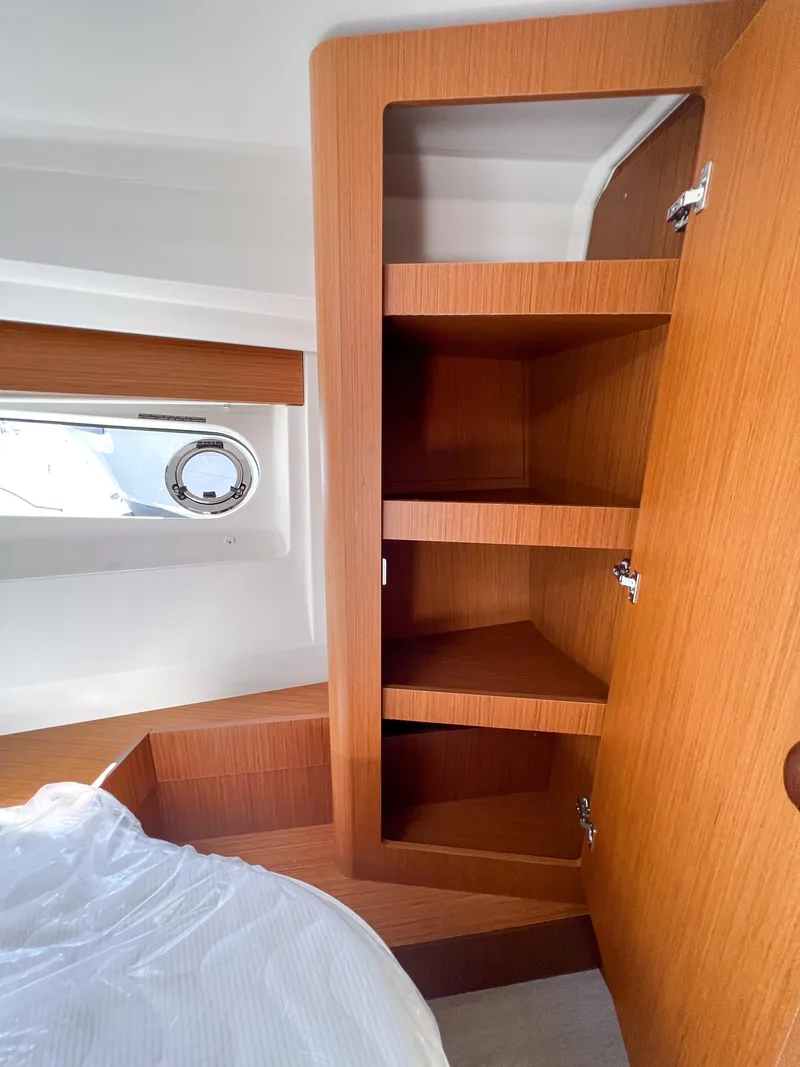 Slide: The Image of 2023 Beneteau Swift Trawler 35 cabin storage with wooden shelves and porthole window. - 13