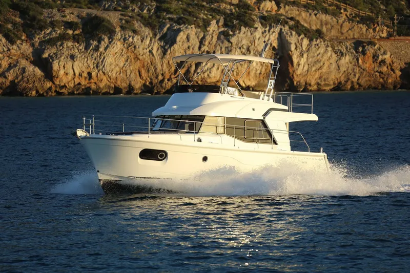 Slide: The Image of 2023 Beneteau Swift Trawler 35 cruising on the water near rocky coastline. - 23