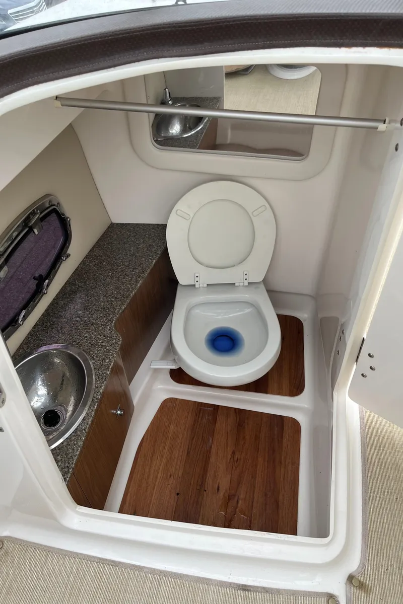Slide: The Image of 2014 Chaparral 257 SSX boat bathroom with toilet, sink, and wood flooring. - 20