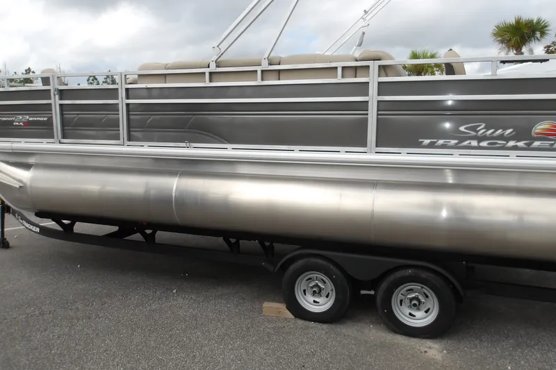 The Image of 2025 Sun Tracker Fishin' Barge 22 XP3 pontoon boat on trailer, side view. - 0