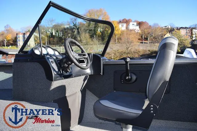 Slide: The Image of 2023 Lund 1875 Fisherman Sport boat interior with steering wheel and seat, Thayer's Marine logo. - 18