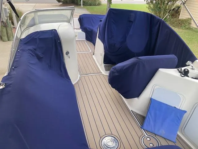 Slide: The Image of 2006 Hurricane SunDeck 237 OB boat interior with blue covers and wooden deck. - 3
