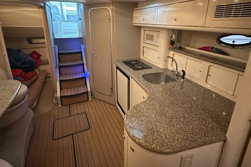 Slide: The Image of 1998 Maxum 3700 SCR yacht interior with kitchenette and stairs, featuring modern amenities. - 40