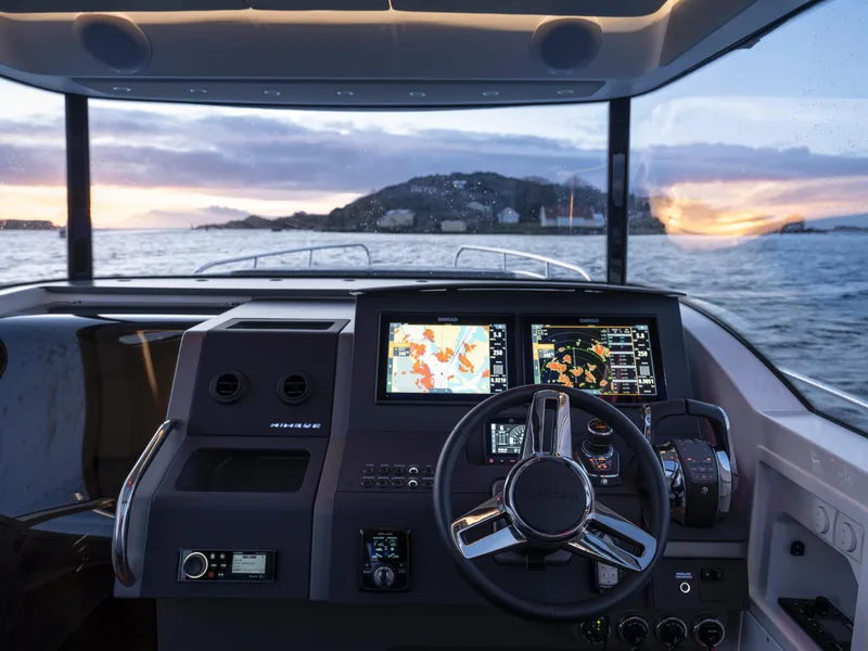 Slide: The Image of 2025 Nimbus C11 boat cockpit with advanced navigation systems at sunset on the water. - 22