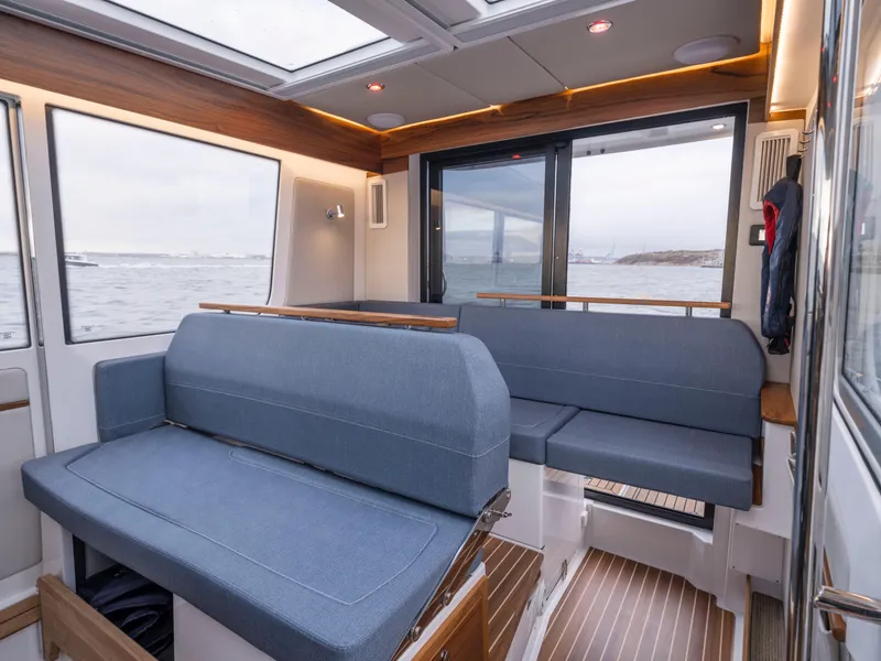 Slide: The Image of Interior of 2025 Nimbus C11 boat with blue seating and ocean view. - 26