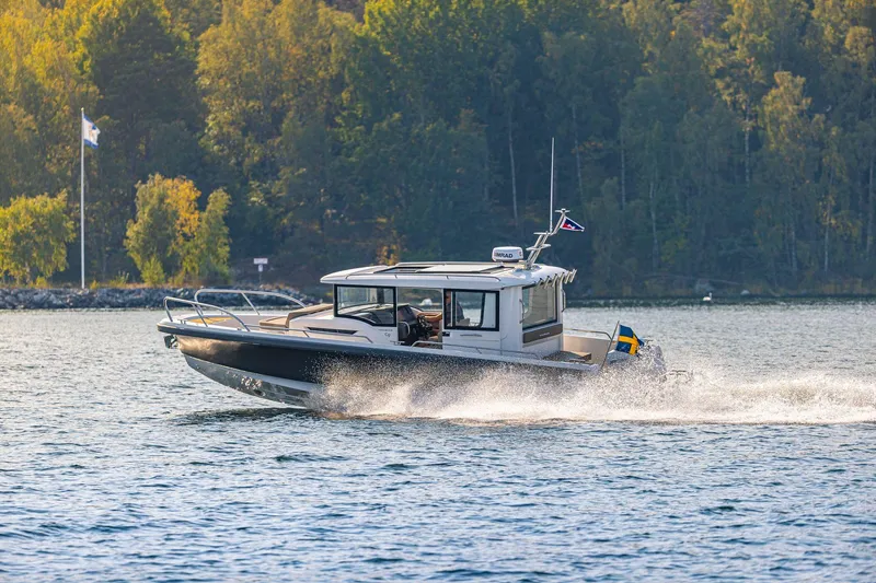 Slide: The Image of Nimbus C9 2025 motorboat cruising on a scenic lake with forested background. - 0