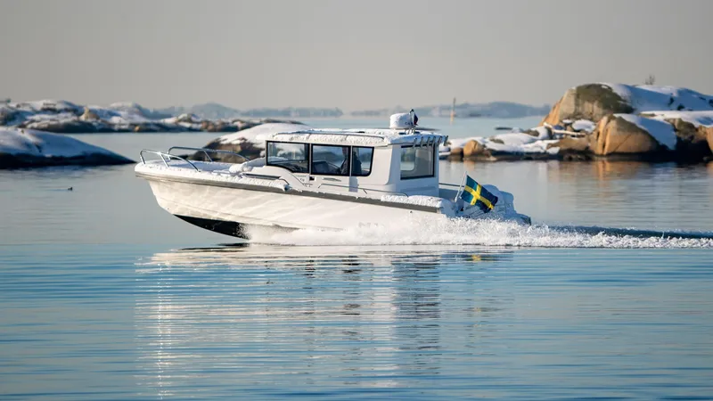 Slide: The Image of Nimbus C9 2025 boat cruising in calm waters with Swedish flag, snowy islands in background. - 12