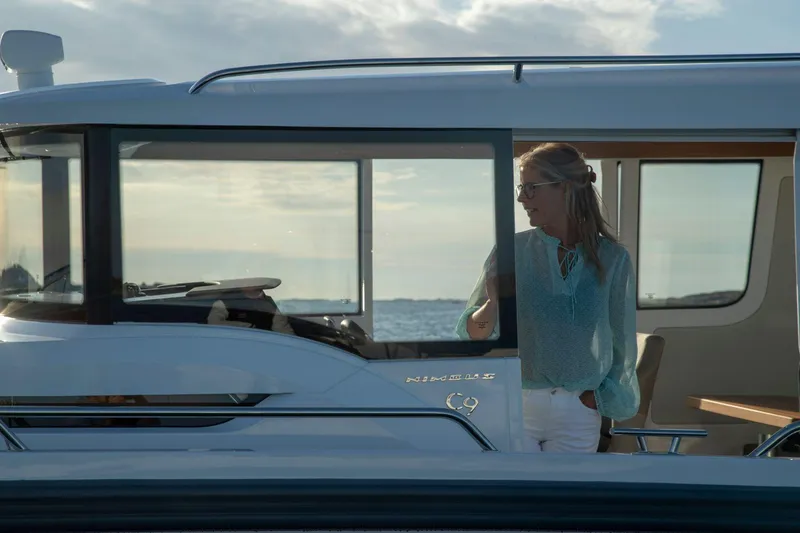 Slide: The Image of Woman on a 2025 Nimbus C9 boat, enjoying a scenic ocean view. - 23