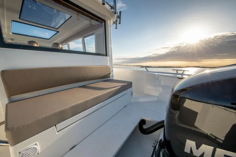 Slide: The Image of Nimbus C9 boat interior with cushioned seating, outboard motor, and ocean view at sunset, 2025 model. - 27