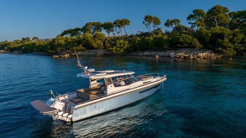 Slide: The Image of Modern Nimbus W11 yacht cruising near a scenic, tree-lined coastline. - 21