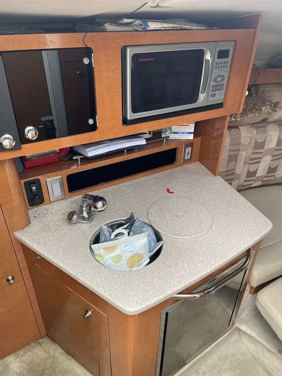 Slide: The Image of 2007 Chaparral 250 Signature boat kitchenette with microwave, sink, and storage cabinets. - 12