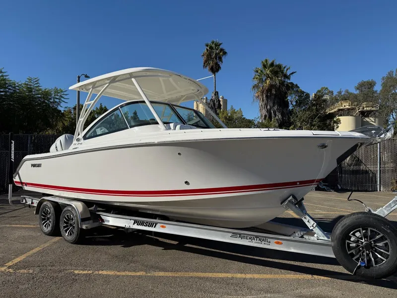 The Image of 2025 Pursuit DC 246 Dual Console boat on trailer, parked outdoors. - 0