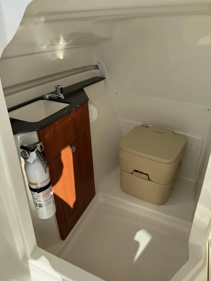 Slide: The Image of 2025 Pursuit DC 246 Dual Console boat interior with sink and portable toilet. - 21