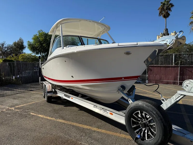 Slide: The Image of 2025 Pursuit DC 246 Dual Console boat on trailer, parked outdoors. - 3