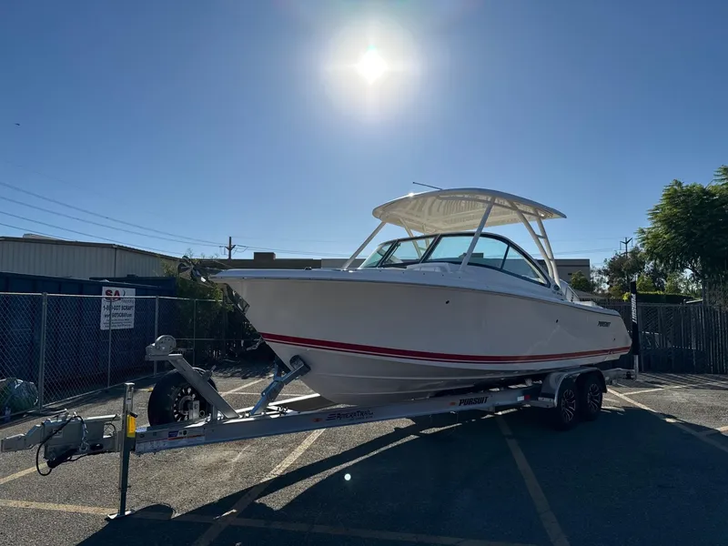 Slide: The Image of 2025 Pursuit DC 246 Dual Console boat on trailer under bright sun. - 4