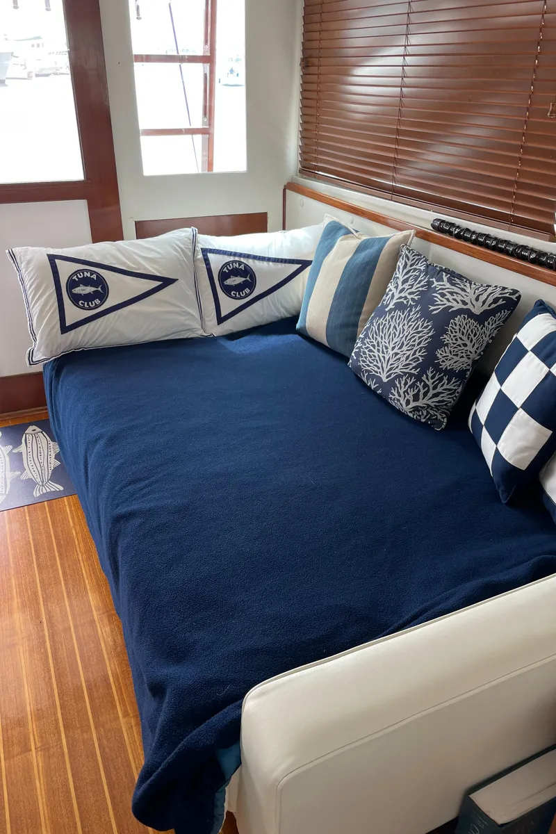Slide: The Image of Cozy interior of 1966 Huckins Sportsman with nautical-themed pillows and blue blanket. - 12