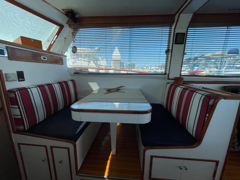 Slide: The Image of Interior of a 1966 Huckins Sportsman boat with striped seating and a dining table. - 18