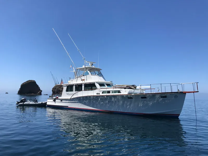 Slide: The Image of 1966 Huckins Sportsman yacht on calm sea with rocky background. - 2