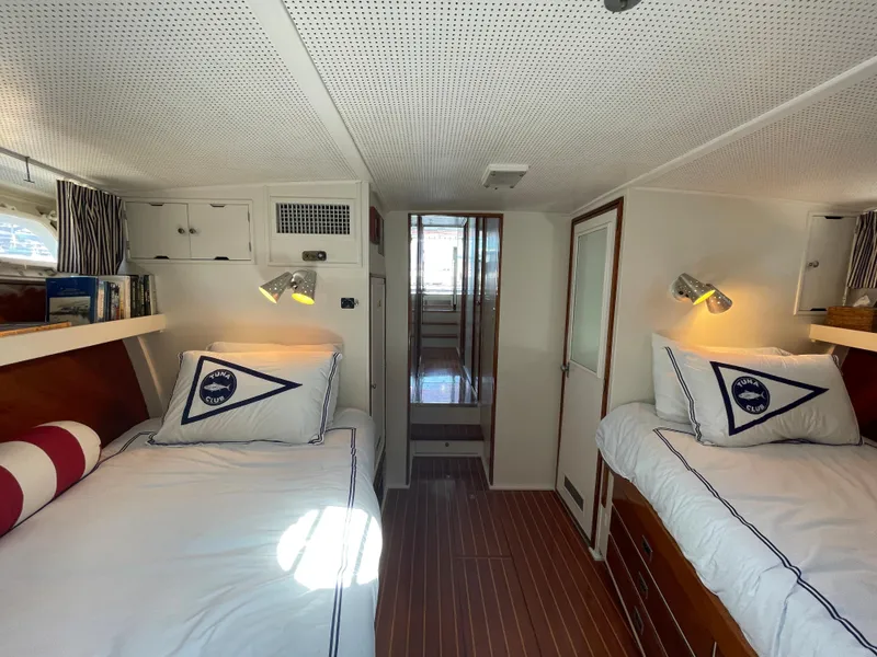 Slide: The Image of 1966 Huckins Sportsman cabin with twin beds, nautical decor, and wood flooring. - 26