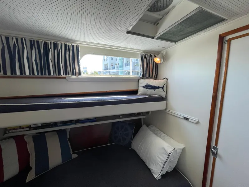 Slide: The Image of 1966 Huckins Sportsman cabin with bunk bed, nautical decor, and striped curtains. - 29