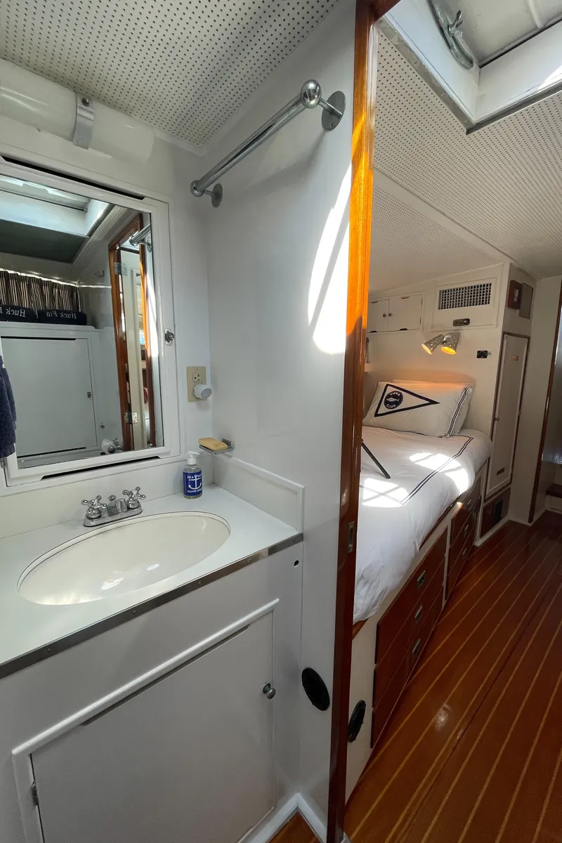 Slide: The Image of 1966 Huckins Sportsman yacht interior with wooden flooring and compact bathroom. - 34