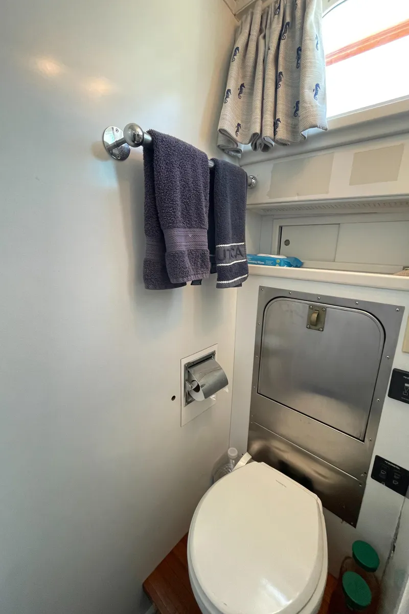 Slide: The Image of 1966 Huckins Sportsman yacht bathroom with towels, toilet, and storage. - 37