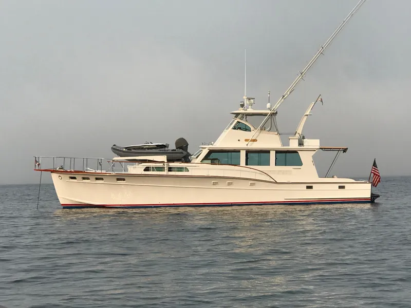 Slide: The Image of 1966 Huckins Sportsman yacht on calm water with American flag. - 4