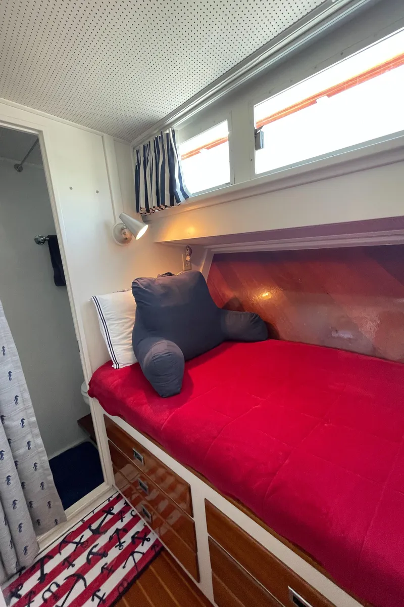 Slide: The Image of 1966 Huckins Sportsman cabin with red bedding and nautical decor. - 40