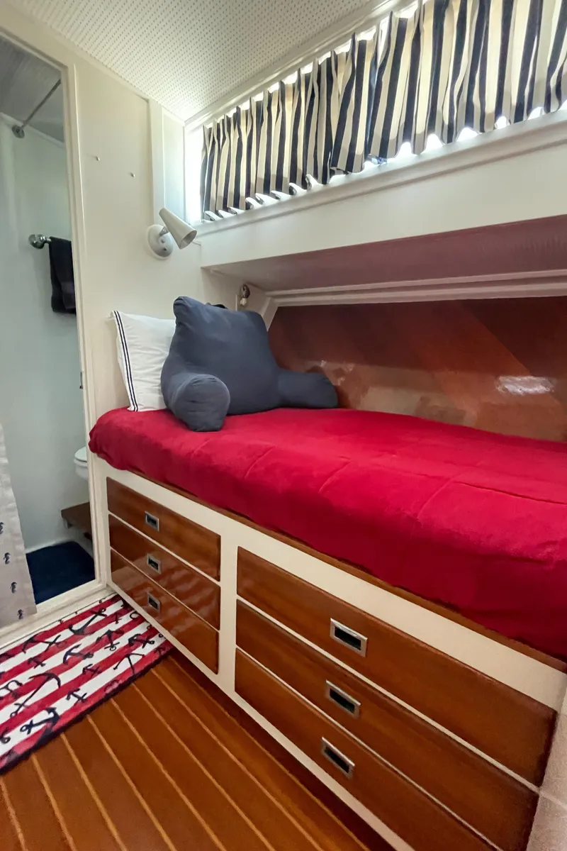 Slide: The Image of 1966 Huckins Sportsman cabin with red bedding, striped curtains, and wooden drawers. - 41