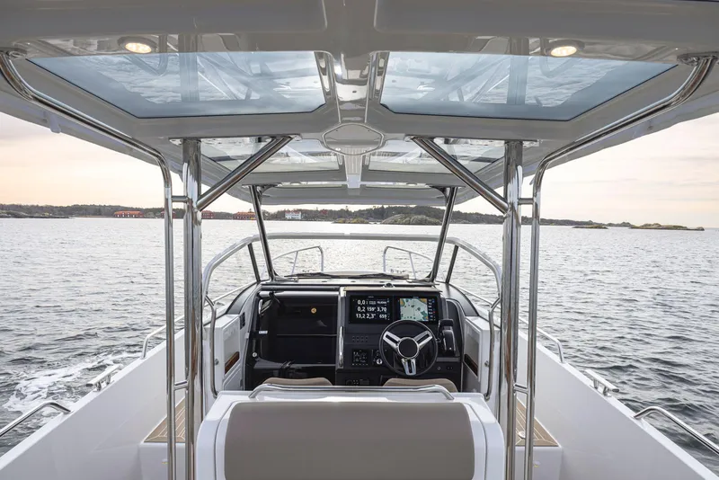 Slide: The Image of 2024 Nimbus Tender 9 boat interior with modern dashboard and steering, overlooking calm waters. - 8