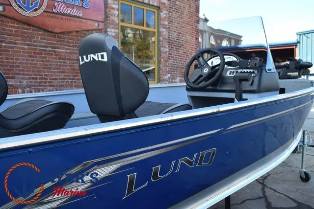 Slide: The Image of 2024 Lund 1600 Fury SS boat, blue exterior, sleek design, parked near brick building. - 25