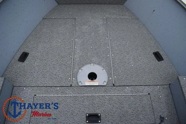Slide: The Image of 2024 Lund 1600 Fury SS boat interior with storage compartments, gray carpet, and Thayer's Marine logo. - 13
