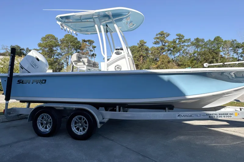 Slide: The Image of 2023 Sea Pro 228 Bay boat on trailer, light blue hull, parked outdoors. - 21