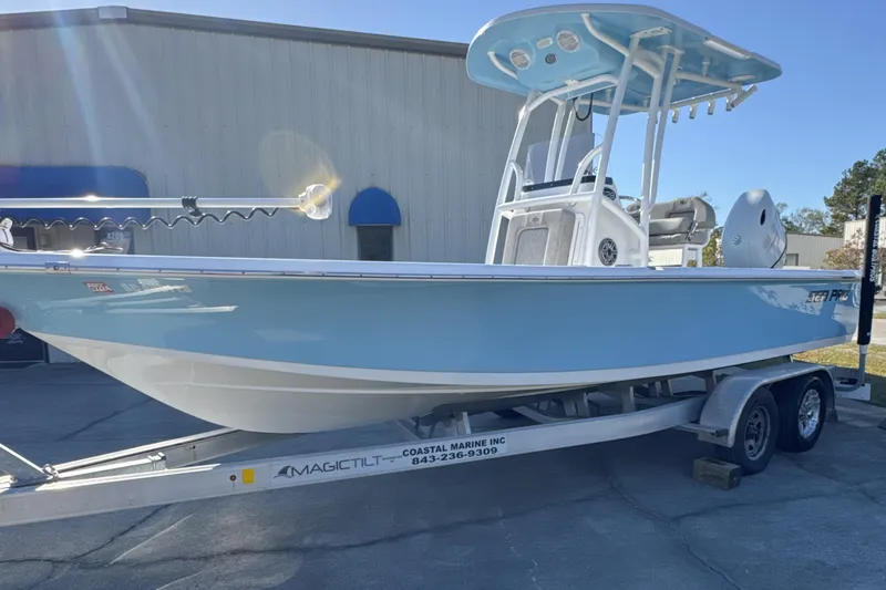 Slide: The Image of 2023 Sea Pro 228 Bay boat on trailer, light blue hull, parked outdoors. - 3