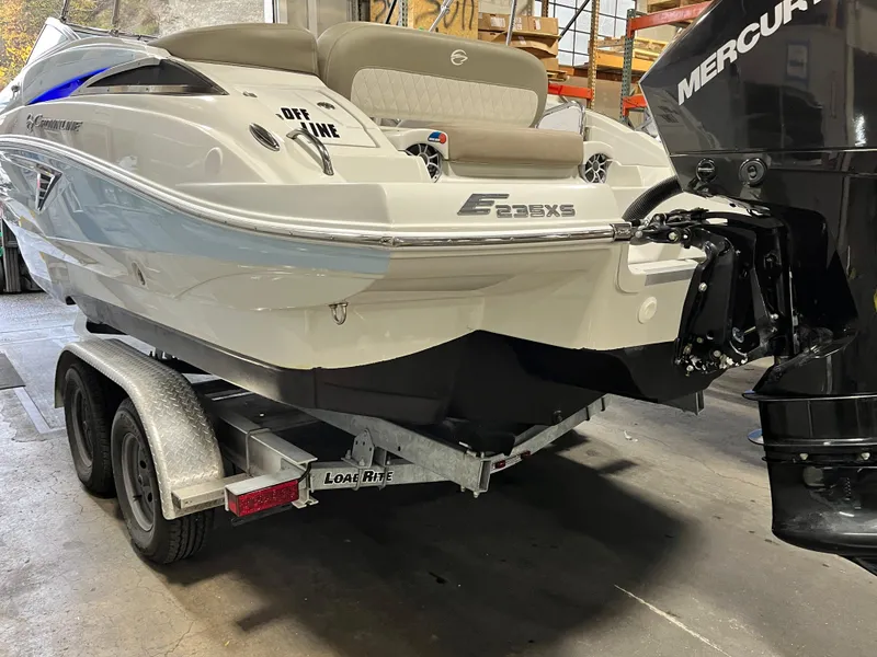 Slide: The Image of 2023 Crownline Eclipse E235 XS boat on trailer, featuring a Mercury outboard motor. - 11