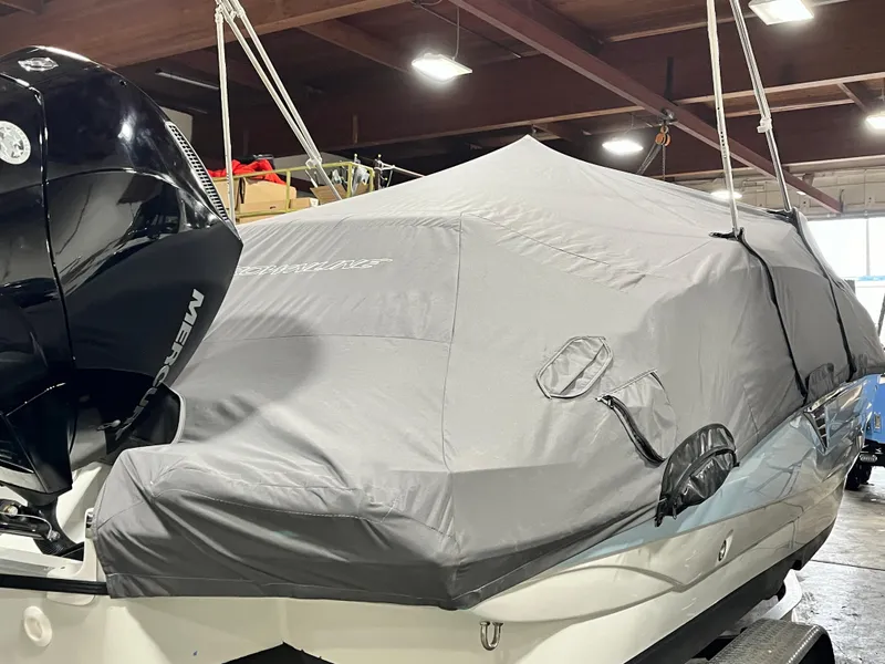 Slide: The Image of 2023 Crownline Eclipse E235 XS boat covered in a protective tarp indoors. - 2