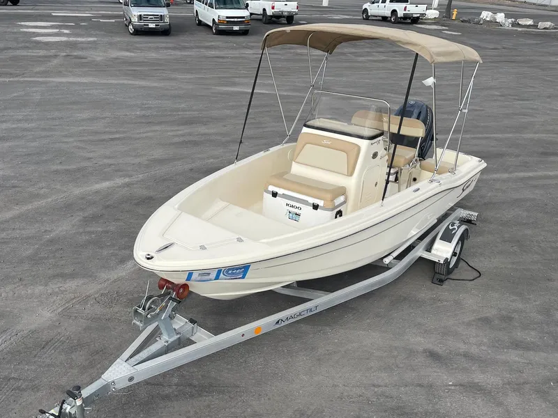Slide: The Image of 2024 Scout 175 Sportfish boat on trailer with canopy, parked in a lot. - 3