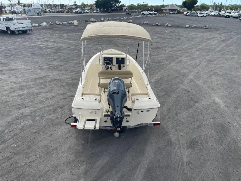 Slide: The Image of 2024 Scout 175 Sportfish boat with canopy and outboard motor in a parking lot. - 6