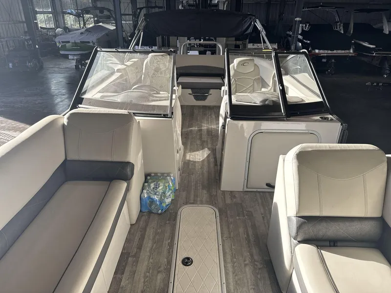 Slide: The Image of 2018 Crest Continental boat interior with beige seating and wood flooring in a showroom. - 9