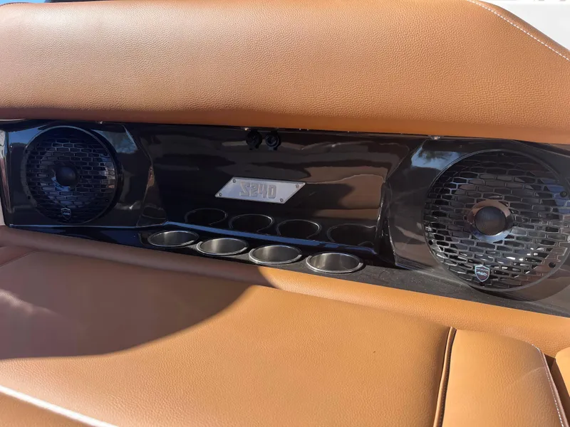 Slide: The Image of 2025 Supreme S240 boat interior with speakers and cup holders, featuring tan leather seating. - 5
