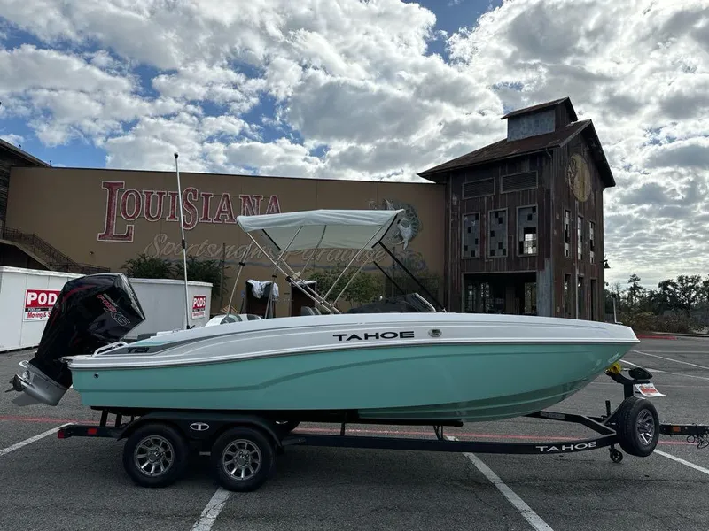 Slide: The Image of 2025 Tahoe T21 boat on trailer, parked in front of Louisiana-themed building. - 2