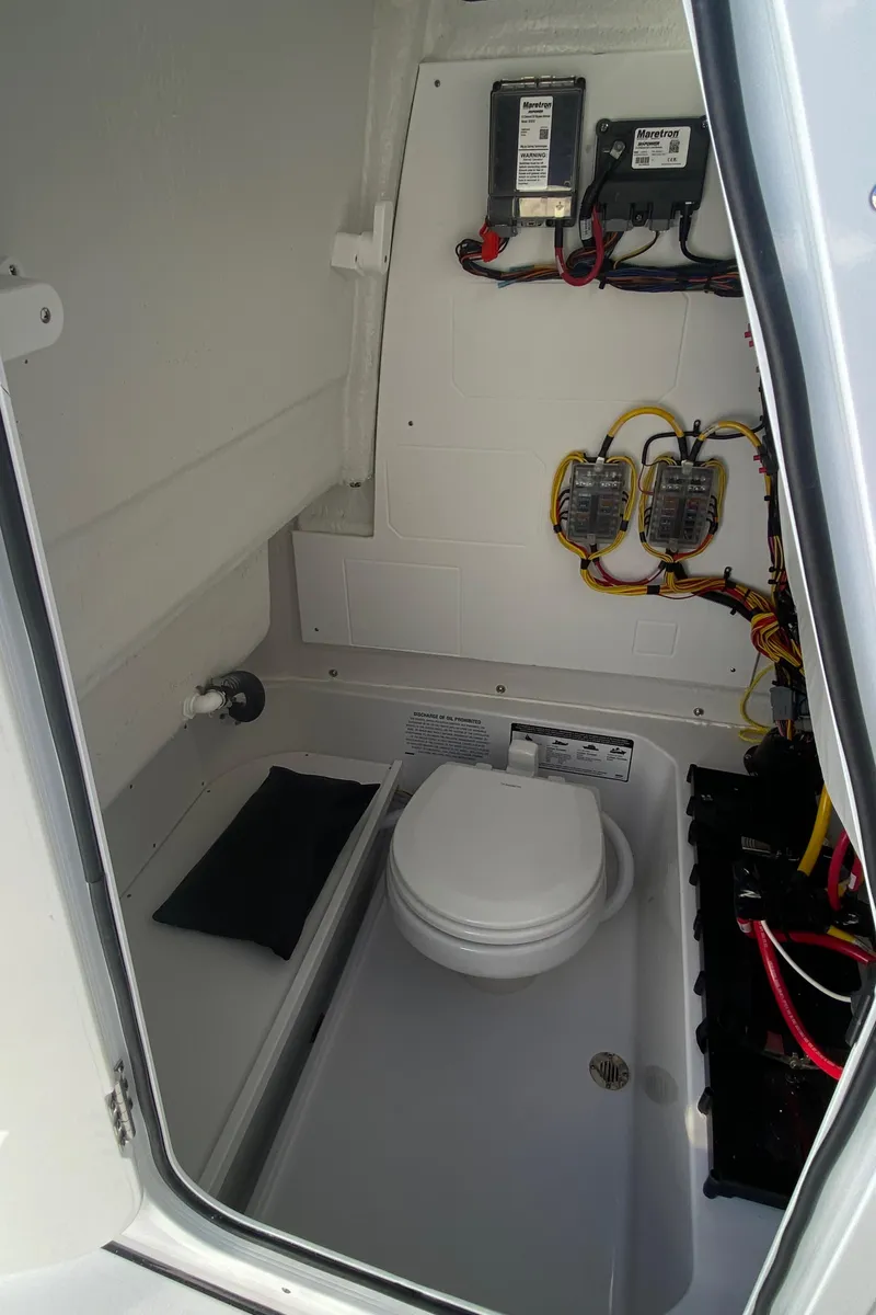 Slide: The Image of 2025 Sportsman Heritage 231 Center Console boat interior with toilet and electrical components. - 11