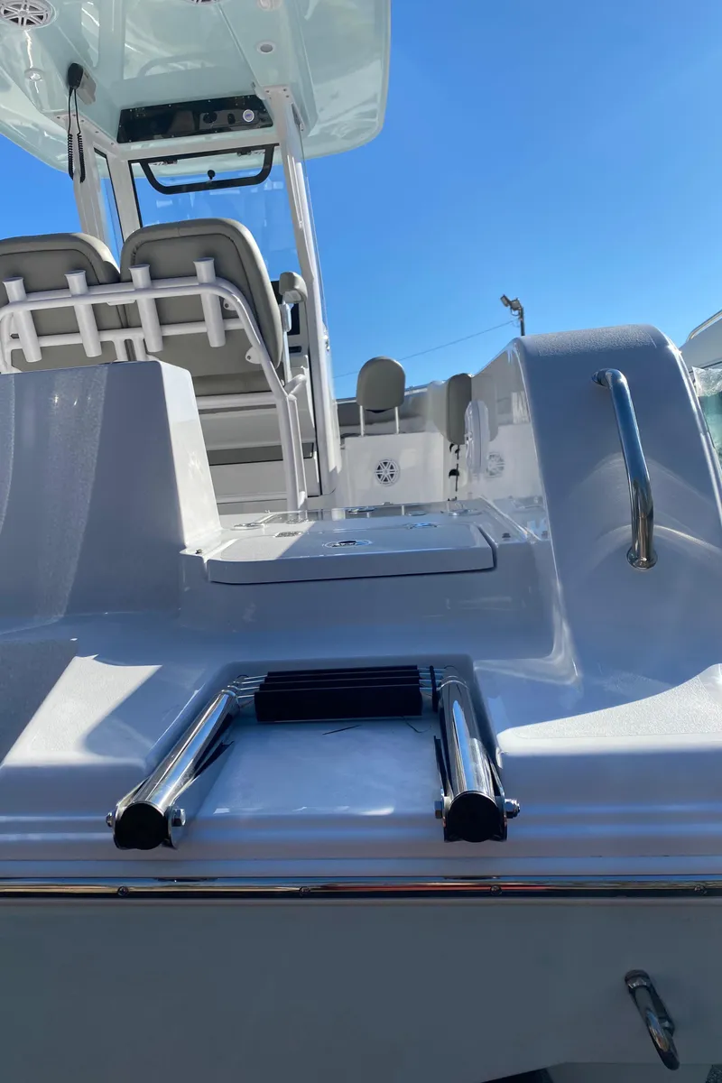 Slide: The Image of 2025 Sportsman Heritage 231 Center Console boat with ladder and seating, under clear blue sky. - 4