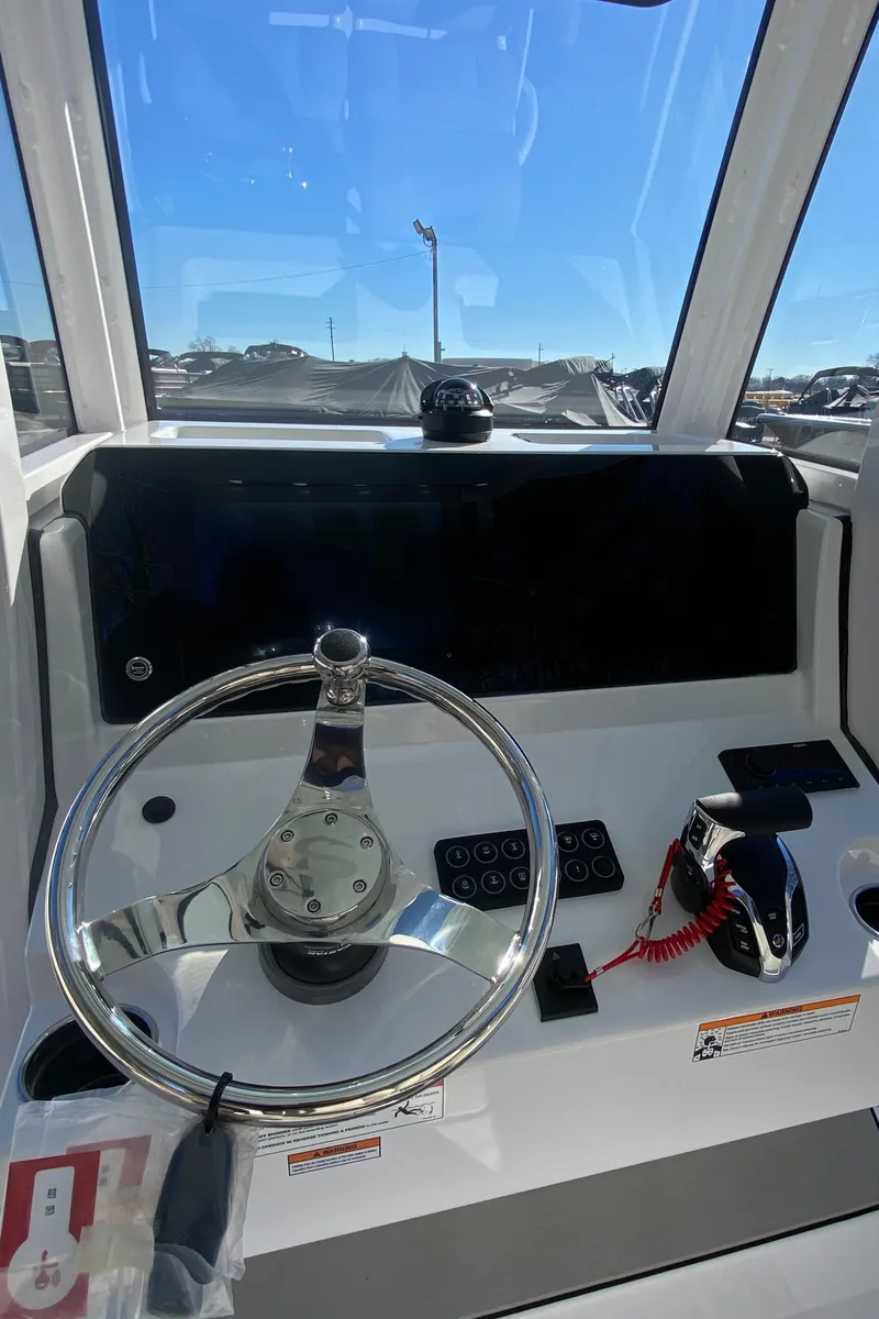 Slide: The Image of 2025 Sportsman Heritage 231 Center Console boat dashboard with steering wheel and controls. - 8