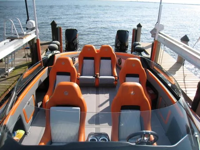 Slide: The Image of 2024 Mystic Powerboats C4000 with orange seats docked by the water. - 11