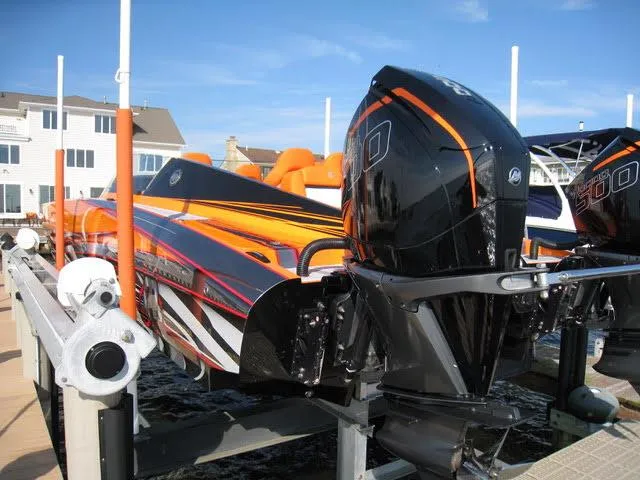 Slide: The Image of 2024 Mystic Powerboats C4000 with vibrant orange and black design on a dock. - 16