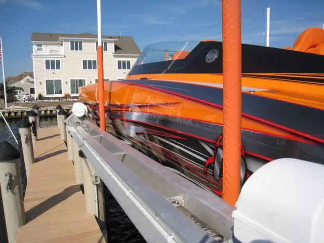 Slide: The Image of 2024 Mystic Powerboats C4000 docked, vibrant orange and black design, waterfront setting. - 17